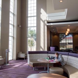 A girl studies in the sunlit lobby of the multi purpose building at TCU's Worth Hills