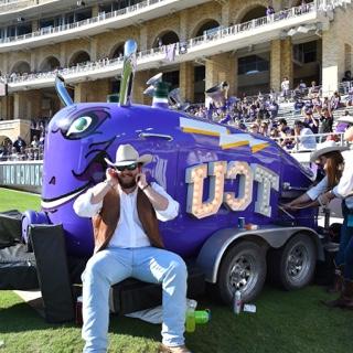 A large purple train horn mounted on a trailer with 的 "TCU" logo lit up in bright white lights